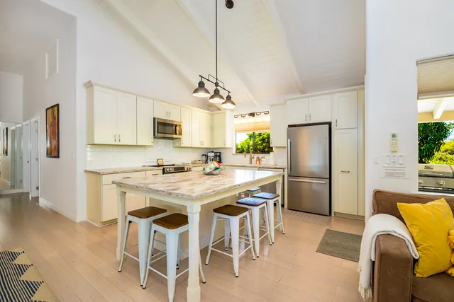 a kitchen with stainless steel appliances granite countertop a refrigerator a stove a microwave a dining table and chairs with wooden floor