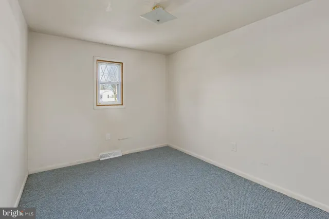 a view of white house with a large tree and wooden fence