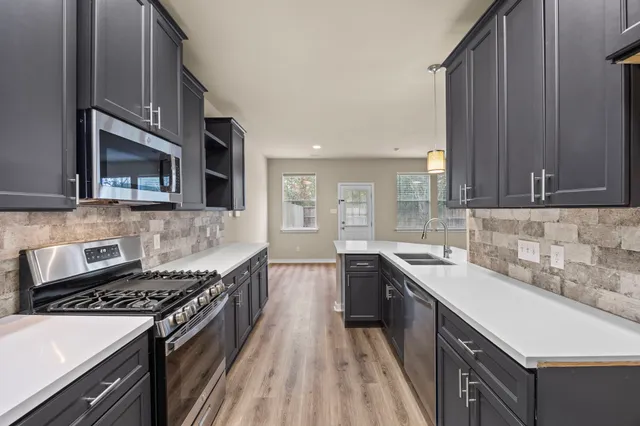 a kitchen with stainless steel appliances a sink stove and cabinets