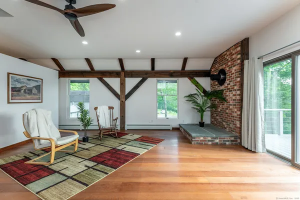 a living room with couch floor to ceiling window and potted plant