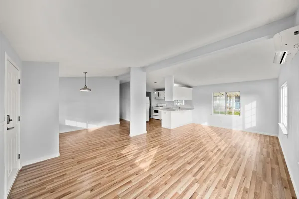 a view of empty room with wooden floor and window