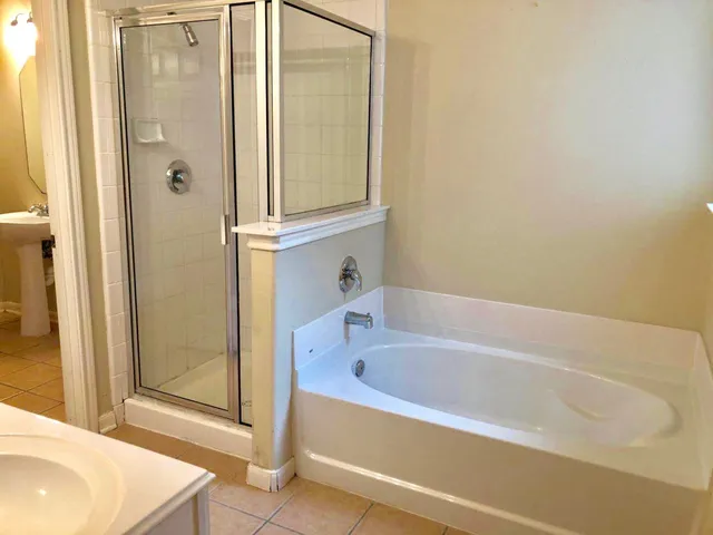 a bathroom with a granite countertop bathtub shower sink vanity and toilet