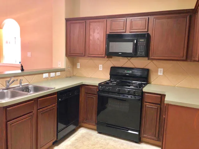 a kitchen with granite countertop a stove top oven microwave and cabinets