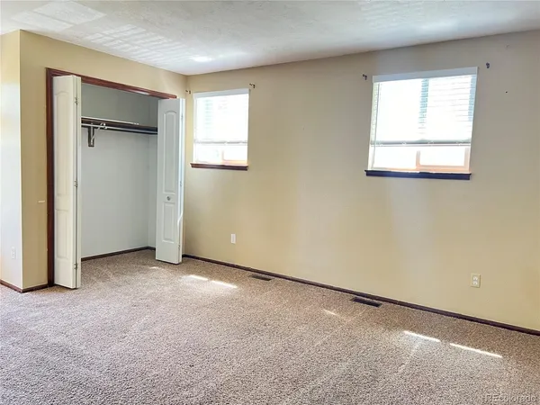 an empty room with windows and closet