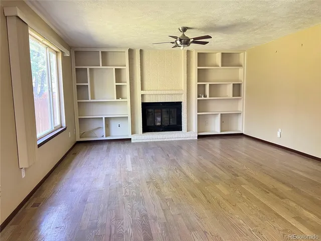 a view of an empty room with a fireplace and a window