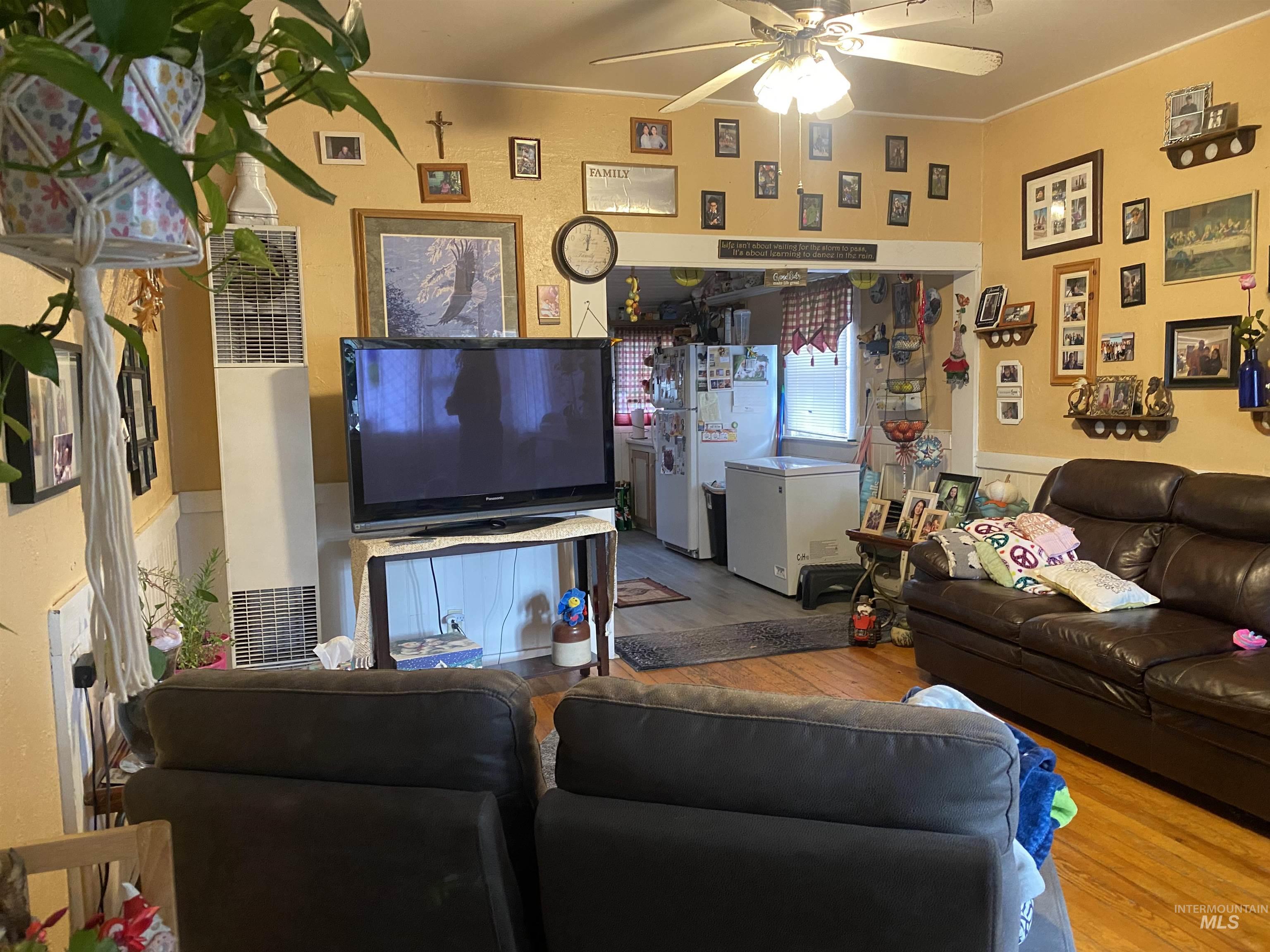 502 East Court Street Weiser, ID 83672 - Photo 3 of 17 Living room featuring wood finished floors, a heating unit, and a ceiling fan