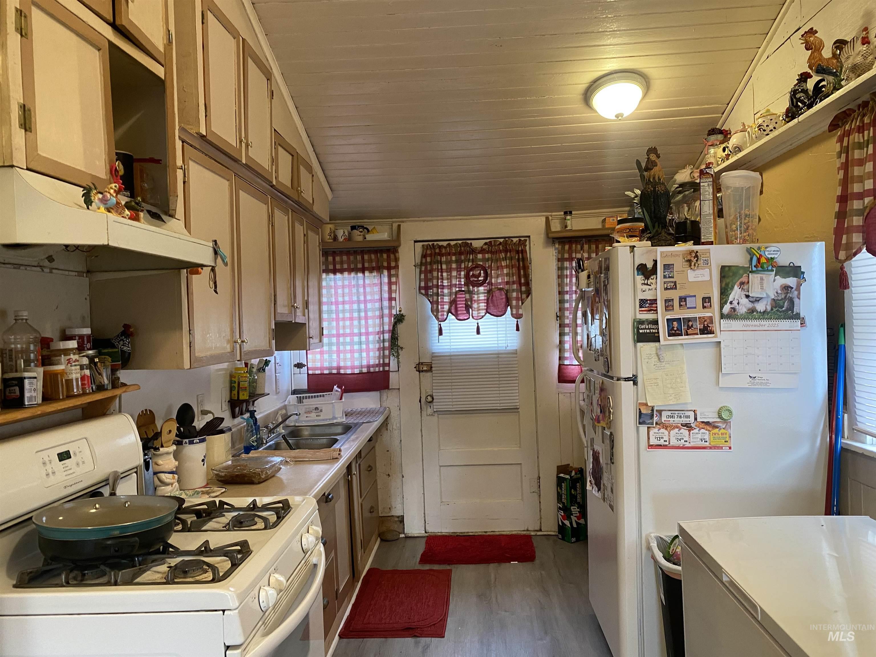 502 East Court Street Weiser, ID 83672 - Photo 5 of 17 Kitchen with white appliances, light countertops, light wood finished floors, under cabinet range hood, and vaulted ceiling