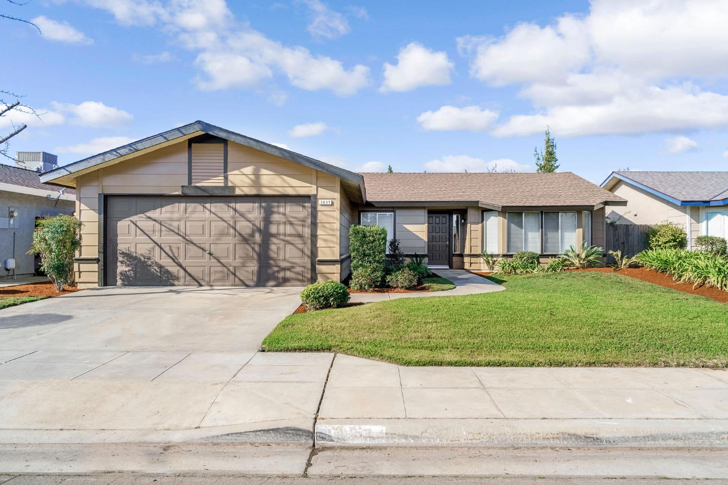 3837 North State Street Fresno, CA 93722 - Photo 1 of 33 a front view of a house with a yard and garage