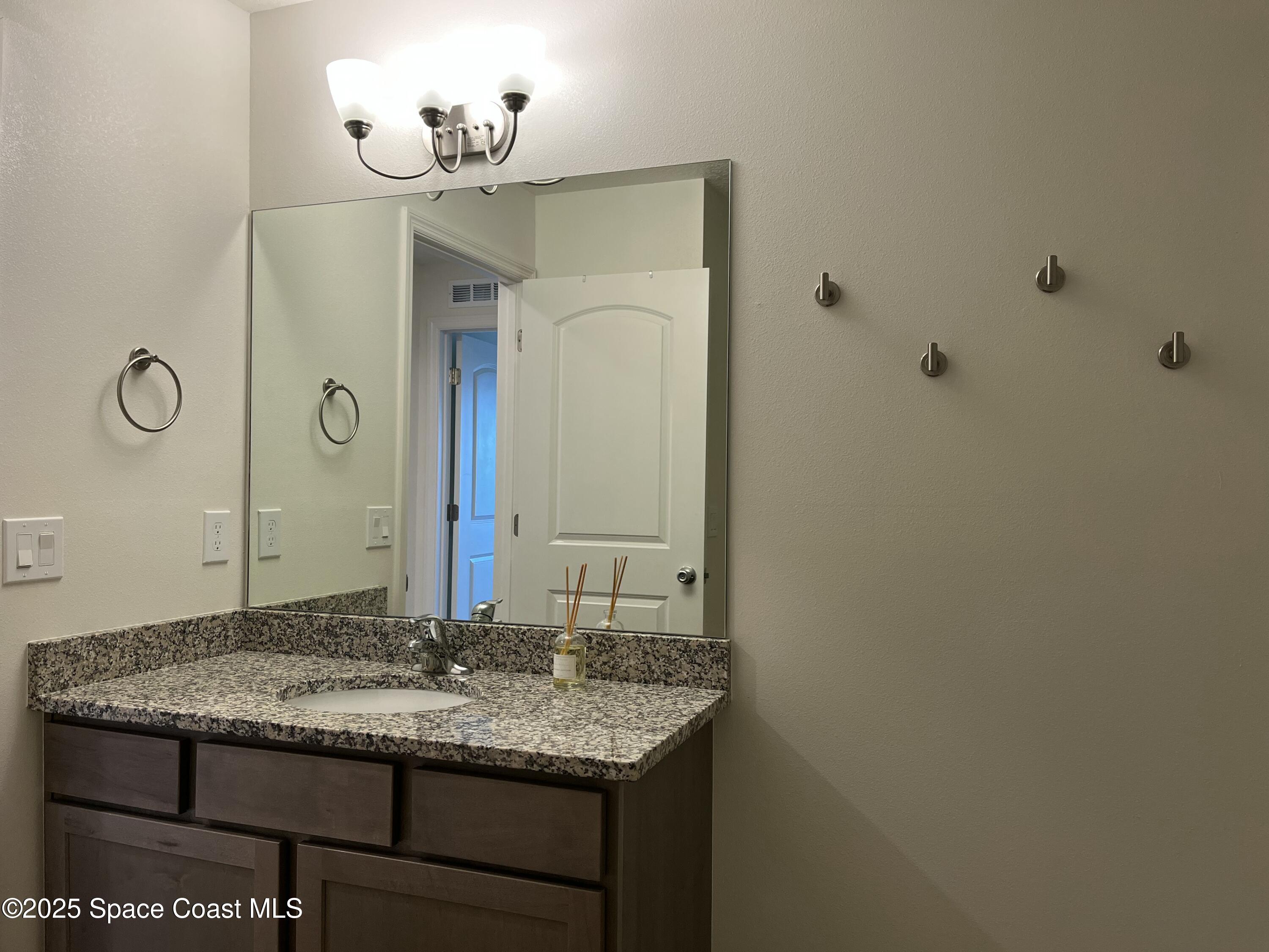 95 Montecito Drive Satellite Beach, FL 32937 - Photo 13 of 20 a bathroom with a granite countertop sink and a mirror