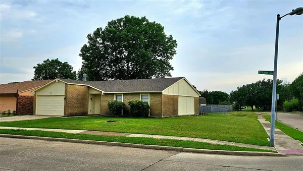 a view of a white house next to a yard with large trees