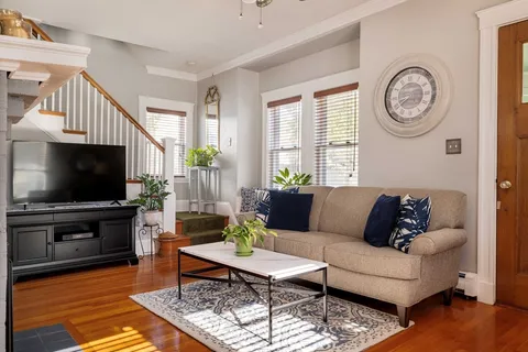 a living room with furniture a flat screen tv and a window