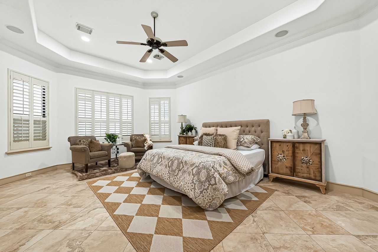 16610 Champagne Falls Court Spring, TX 77379 - Photo 20 of 50 Enormous Primary Bedroom with plantation shutters, elegant tiled flooring, built ins, & ceiling fan.