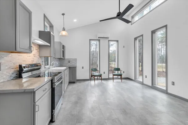 a kitchen with stainless steel appliances a stove a sink a refrigerator and chairs