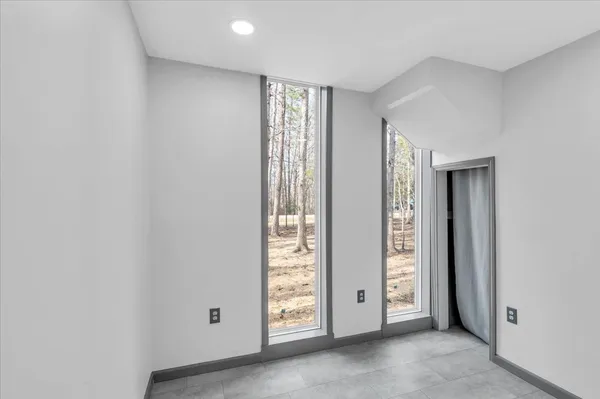 a view of an empty room with wooden floor and windows