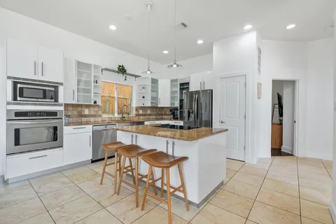 a kitchen with stainless steel appliances kitchen island granite countertop a refrigerator and a stove top oven