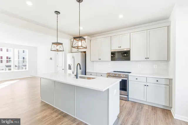 a kitchen with stainless steel appliances granite countertop a sink a stove a refrigerator and white cabinets with wooden floor