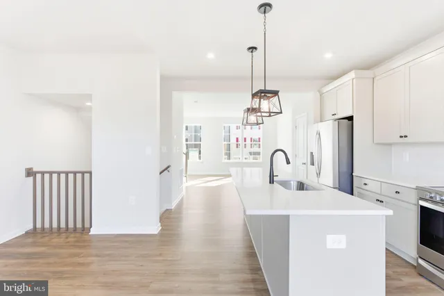 a kitchen with kitchen island a stove a sink a center island a refrigerator and a wooden floor