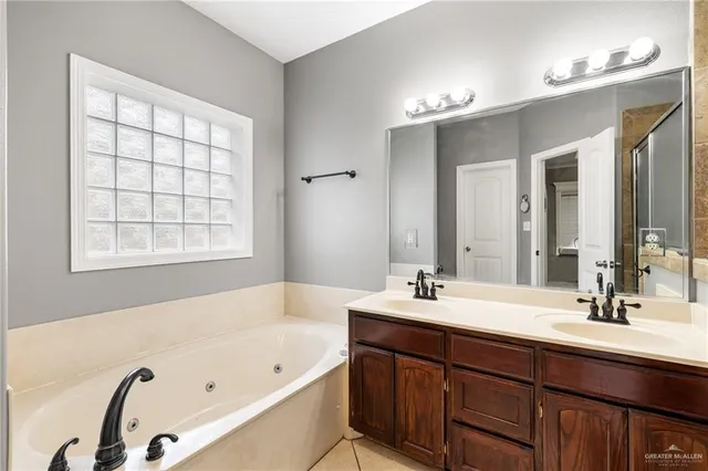 a bathroom with a tub a sink double vanity and a mirror