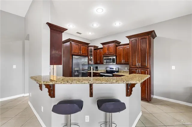 a kitchen with stainless steel appliances granite countertop a sink a stove a refrigerator a center island and chairs