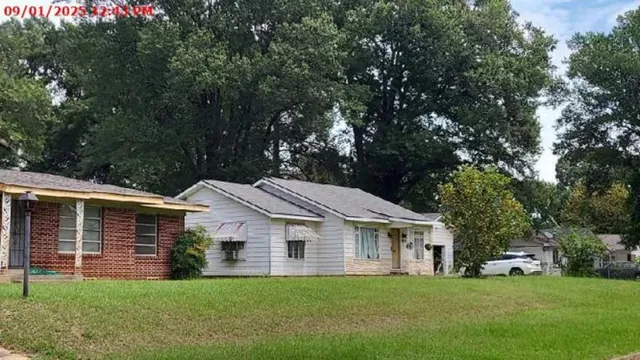 a front view of a house with a yard and trees