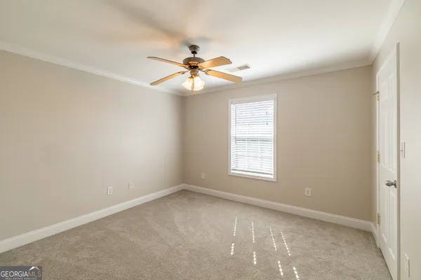 an empty room with windows and fan
