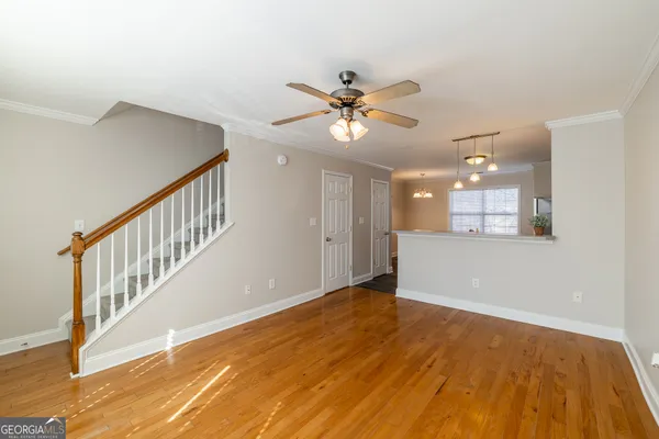 a view of an empty room with wooden floor and a chandelier fan