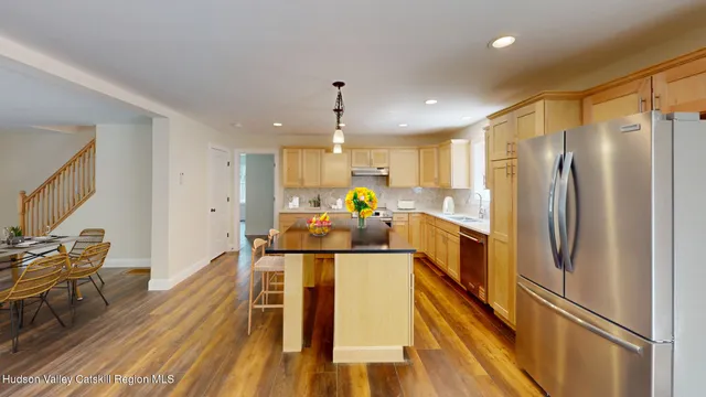 a kitchen with a refrigerator a stove and white cabinets with wooden floor