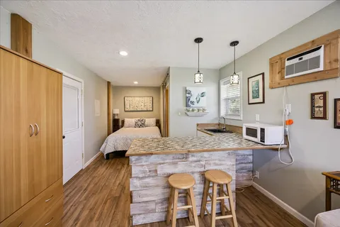 a living room with stainless steel appliances granite countertop furniture and a wooden floor