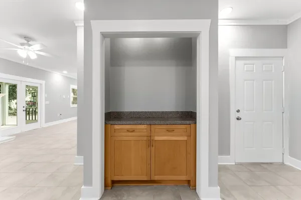 a view of an empty room with window and chandelier fan