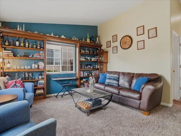 a living room with furniture a bookshelf and a window