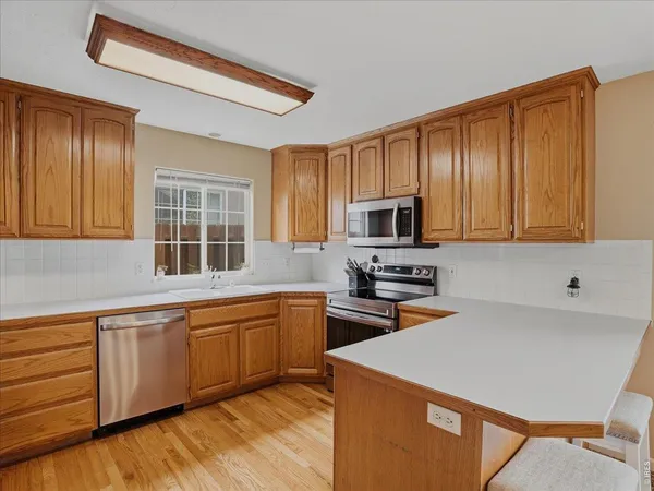 a kitchen with stainless steel appliances granite countertop wooden cabinets a sink and dishwasher a stove with wooden floor