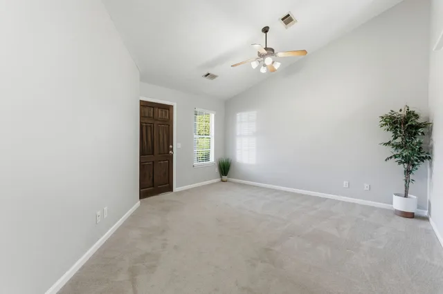 an empty room with a chandelier fan and windows