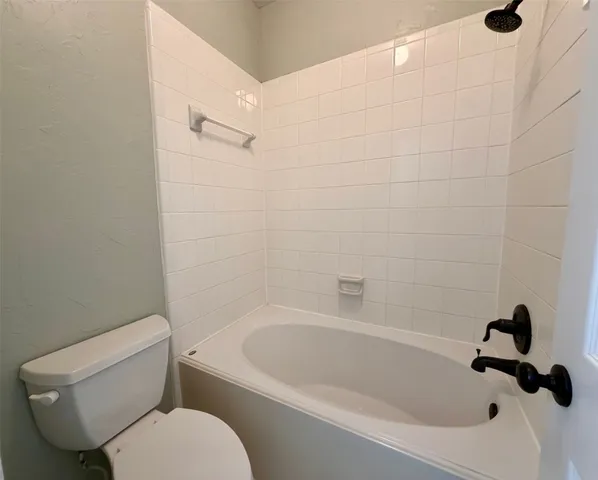 a white toilet sitting next to a bathtub