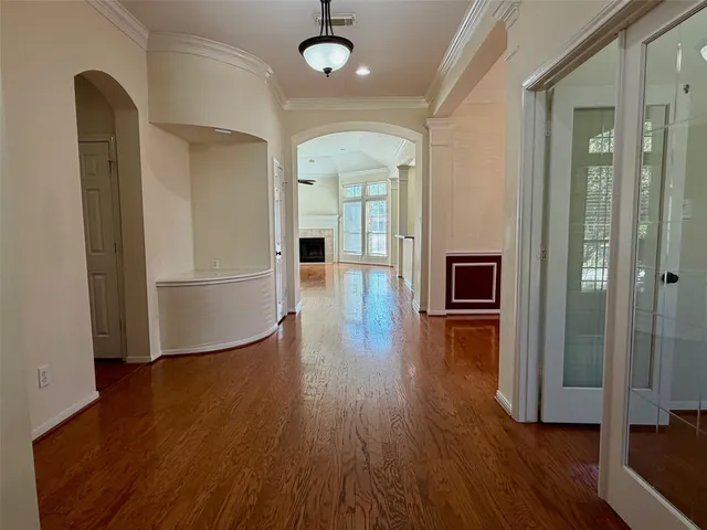 a view of a hallway with wooden floor and livingroom with furniture