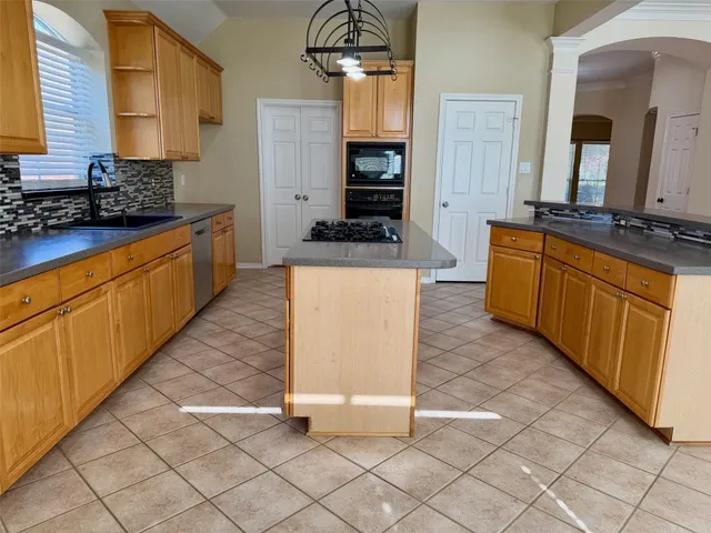a large kitchen with stainless steel appliances a stove a sink and a microwave