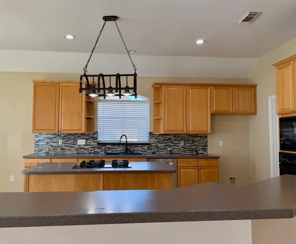 a kitchen with stainless steel appliances granite countertop a stove a sink and a refrigerator