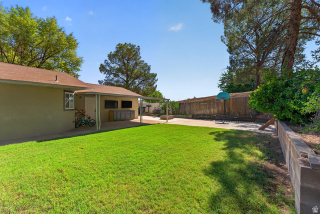 1690 Maplewood Way St. George, UT 84790 - Photo 13 of 17 Expansive backyard with mature landscaping and lush lawn, complemented by a single-story residence featuring a covered patio area