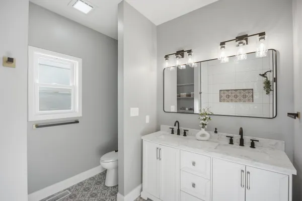 a bathroom with a granite countertop sink toilet and mirror