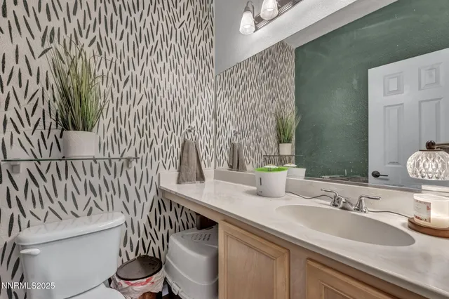 a bathroom with a granite countertop sink and a toilet