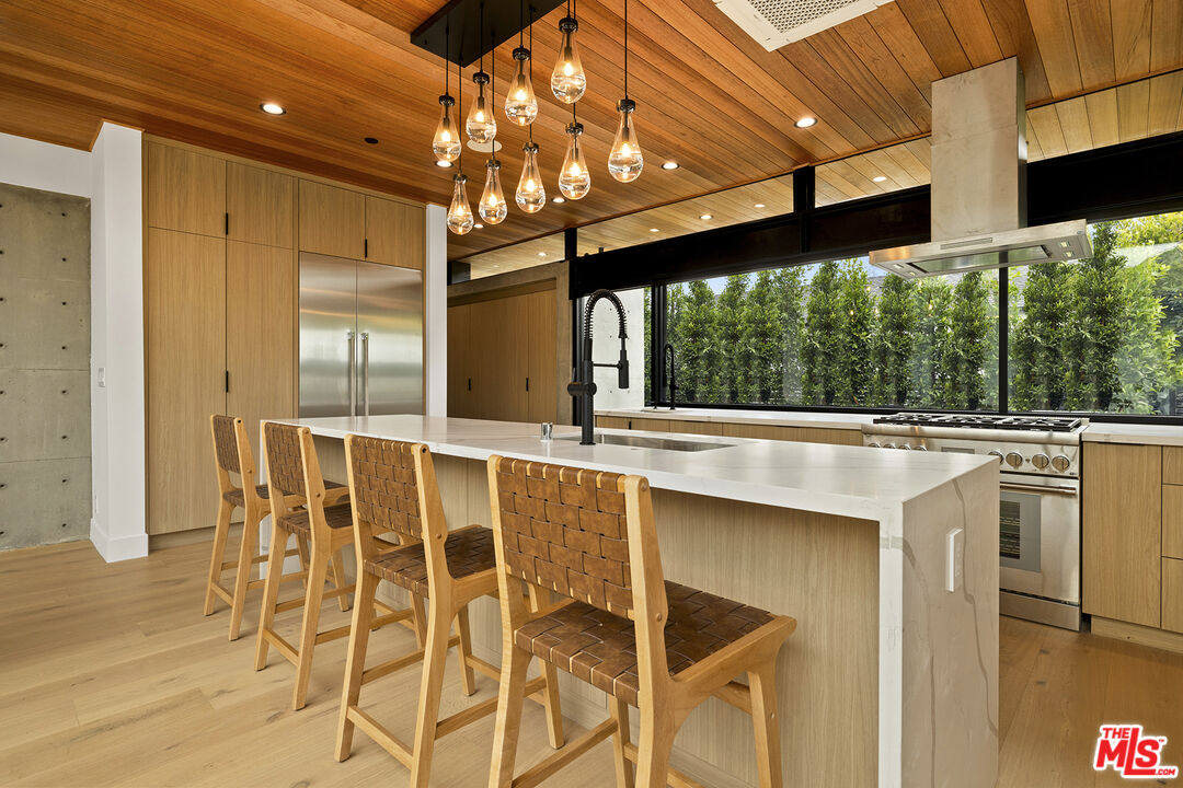 5707 Busch Drive Malibu, CA 90265 - Photo 13 of 35 a kitchen with stainless steel appliances kitchen island granite countertop a table chairs and a large window
