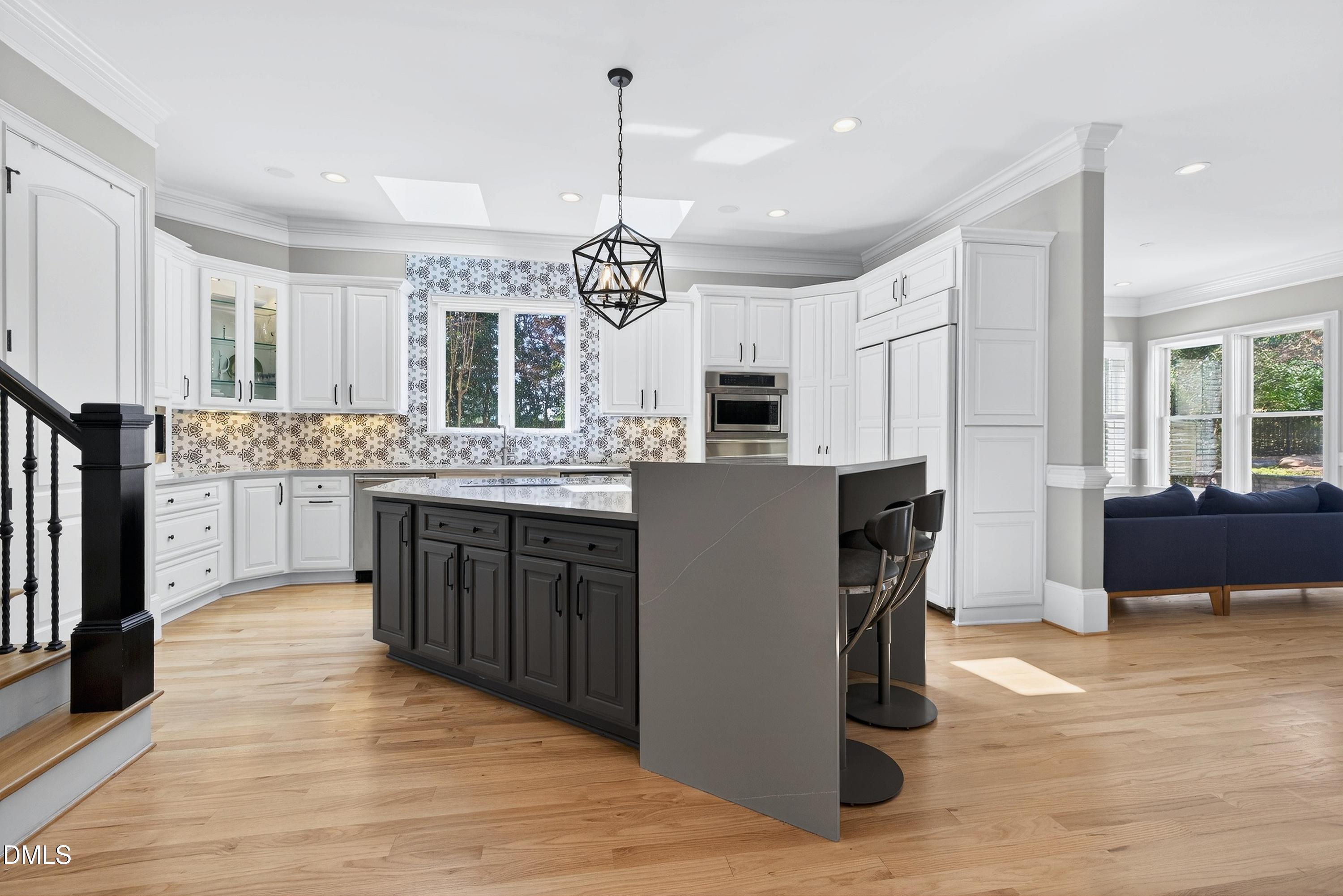 6701 Foxfire Place Raleigh, NC 27615 - Photo 23 of 67 a kitchen with kitchen island granite countertop wooden floors and white cabinets