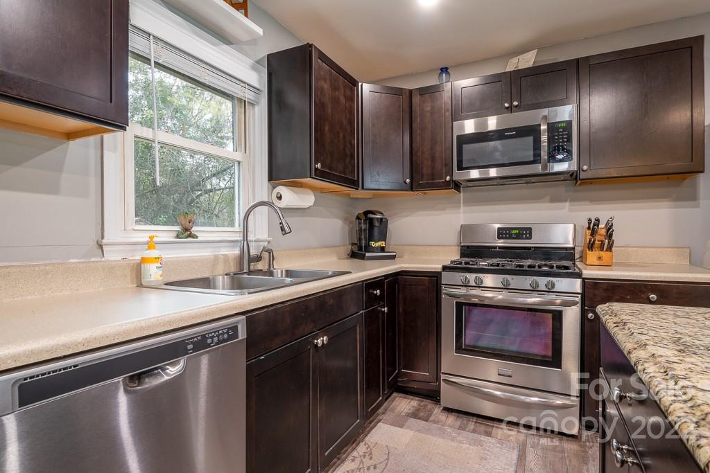 626 Westside Terrace, Unit 5 Davidson, NC 28036 - Photo 9 of 24 a kitchen with stainless steel appliances granite countertop a sink a stove a microwave and wooden cabinets
