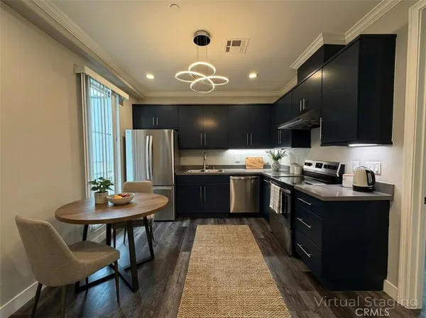 a kitchen with stainless steel appliances kitchen island granite countertop a sink dishwasher a stove a refrigerator with a dining table and chairs