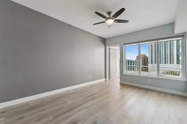 a view of an empty room with window and wooden floor