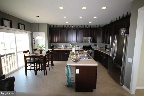 a kitchen with kitchen island granite countertop a refrigerator a stove a sink a dining table and chairs