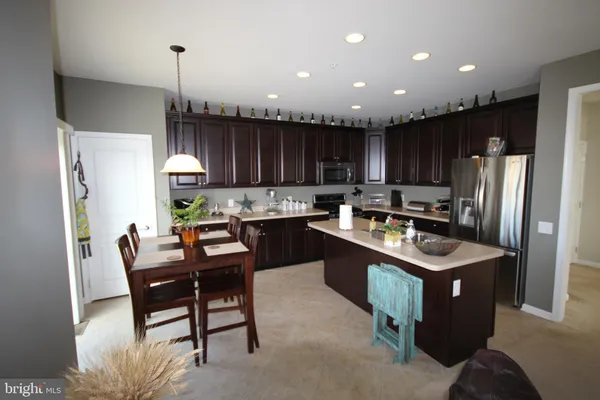 a kitchen with a refrigerator a stove a sink and a dining table with wooden floor