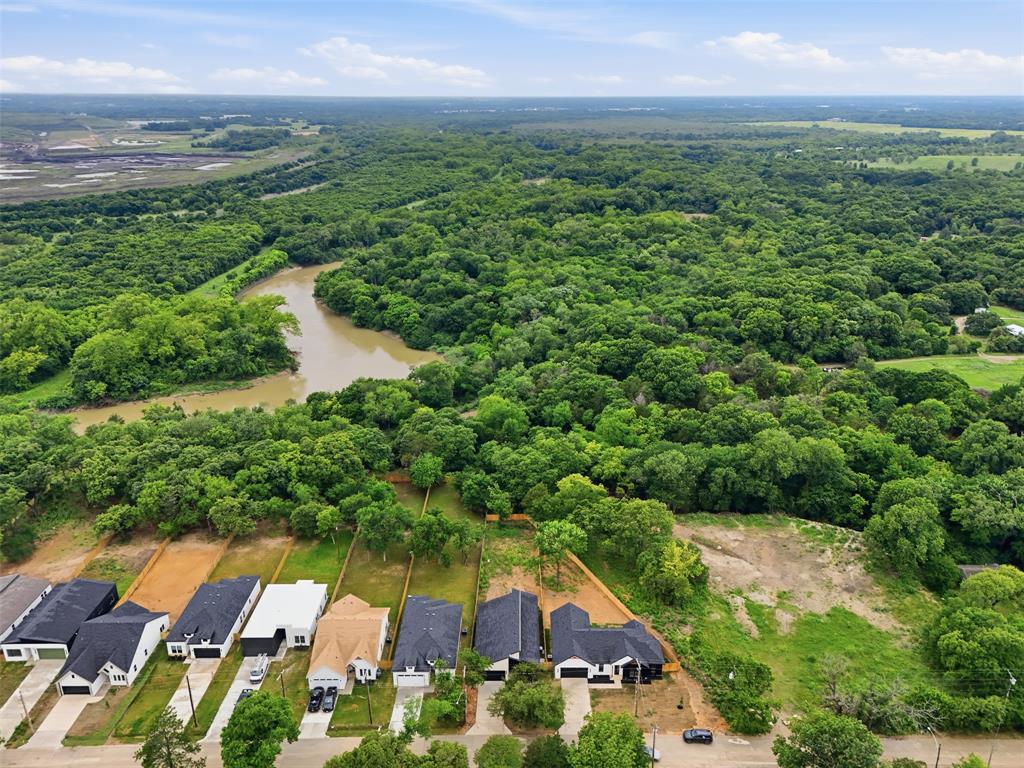 1111 Riverwood Road Dallas, TX 75217 - Photo 38 of 40 Aerial perspective showcasing a residential street with diverse architectural styles bordering a dense forest and a winding river