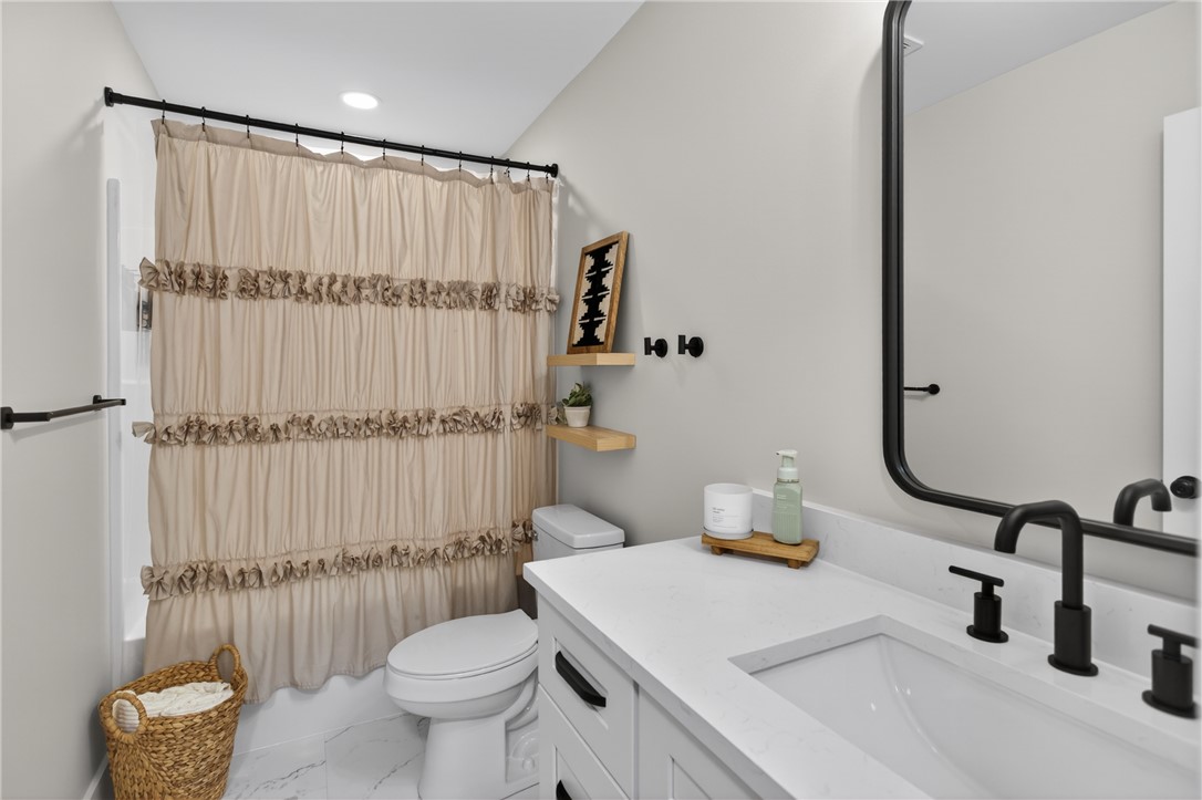 106 Bolt Road Townville, SC 29689 - Photo 20 of 33 A well-appointed bathroom features a bright white vanity with a sleek black faucet, complemented by modern floating shelves.
