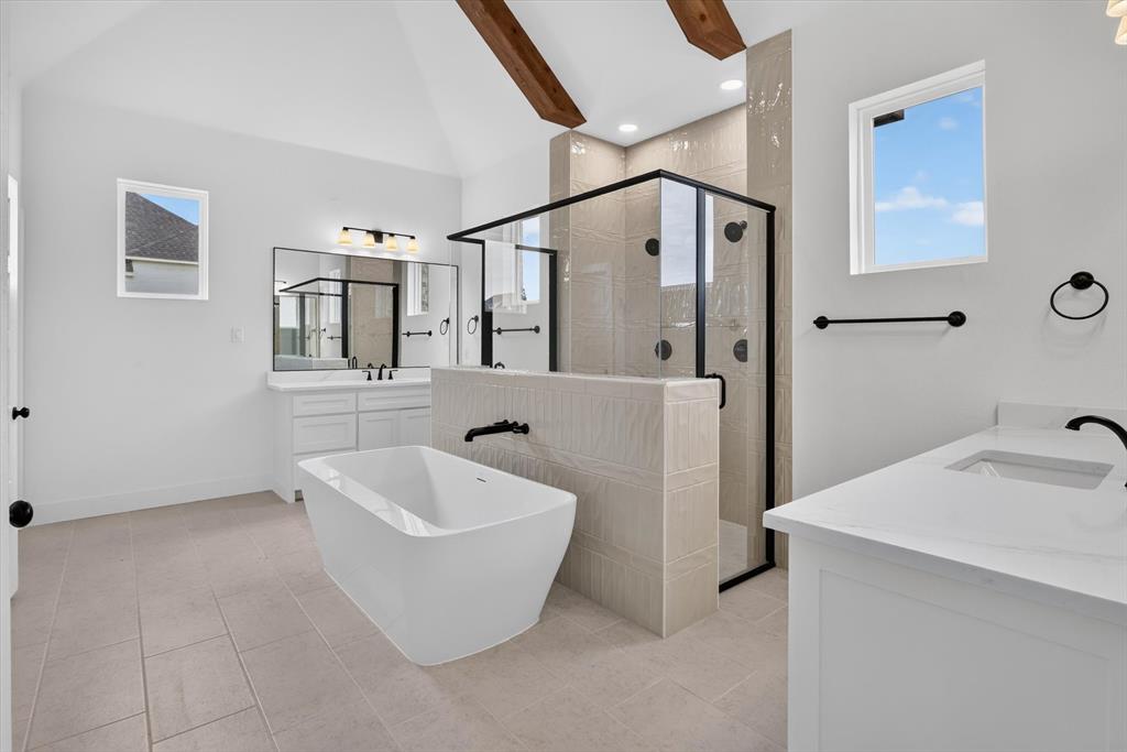 471 Red Bird Drive Springtown, TX 76082 - Photo 19 of 35 Spacious bathroom featuring a freestanding soaking tub, a large walk-in shower with black-framed glass enclosure, and dual vanity areas with white cabinetry and solid surface countertops