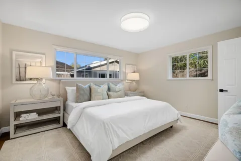 a bedroom with a white bed and dresser with mirror